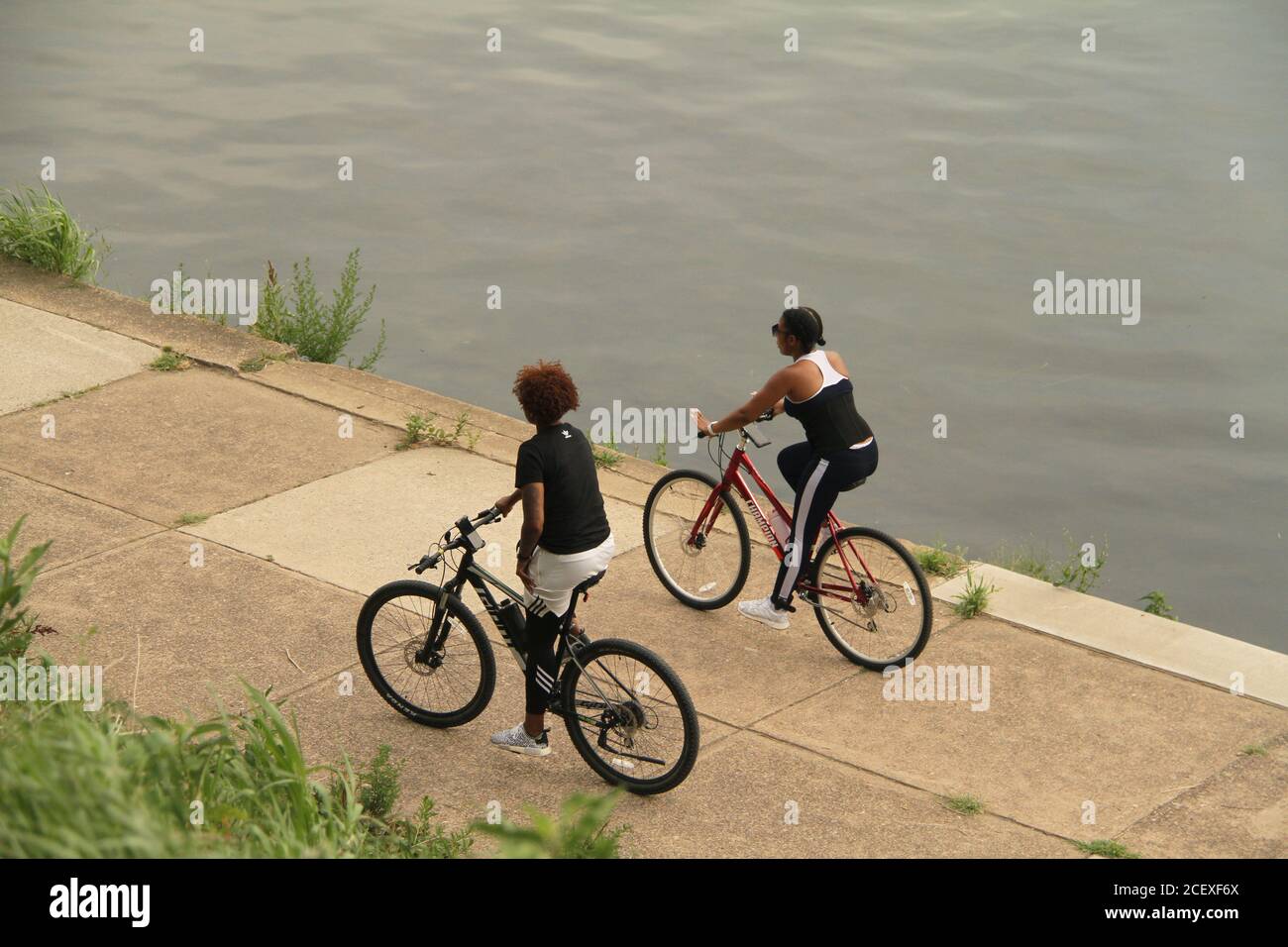 Young people riding bicycles by a river in the U.S.A. Stock Photo