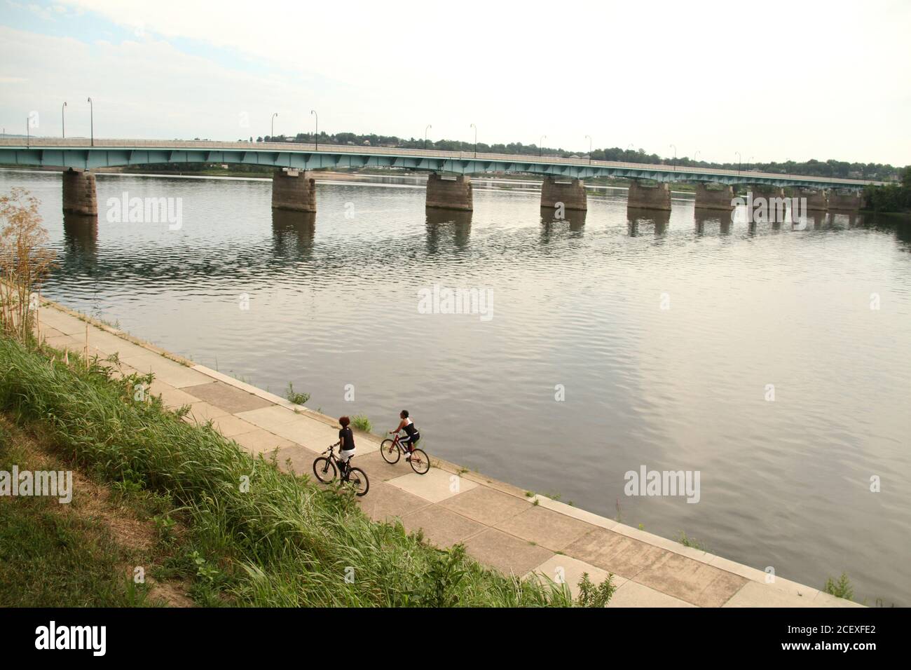 Bridge over the Susquehanna River in Harrisburg, PA, USA. Young people riding bikes on the Riverwalk. Stock Photo
