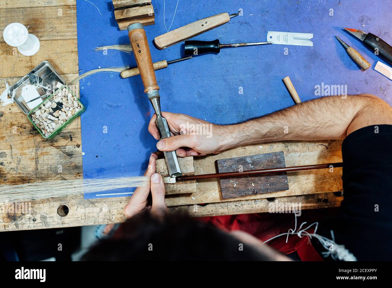 Top view of crop skilled artisan luthier using chisel while making violin bow in workshop Stock Photo