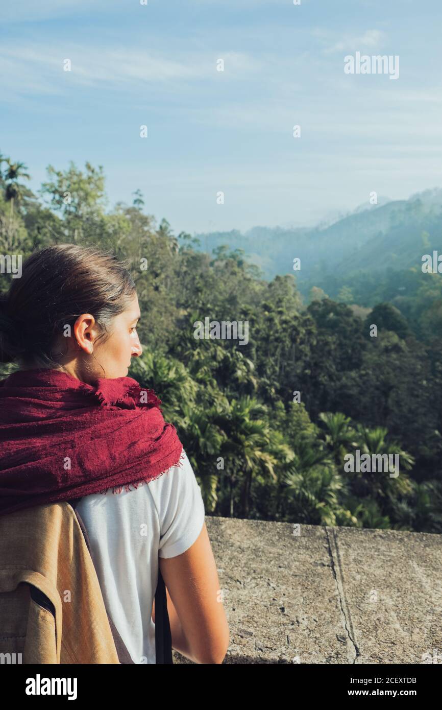 Back view of ethnic female hiker with backpack standing on stone bridge ...