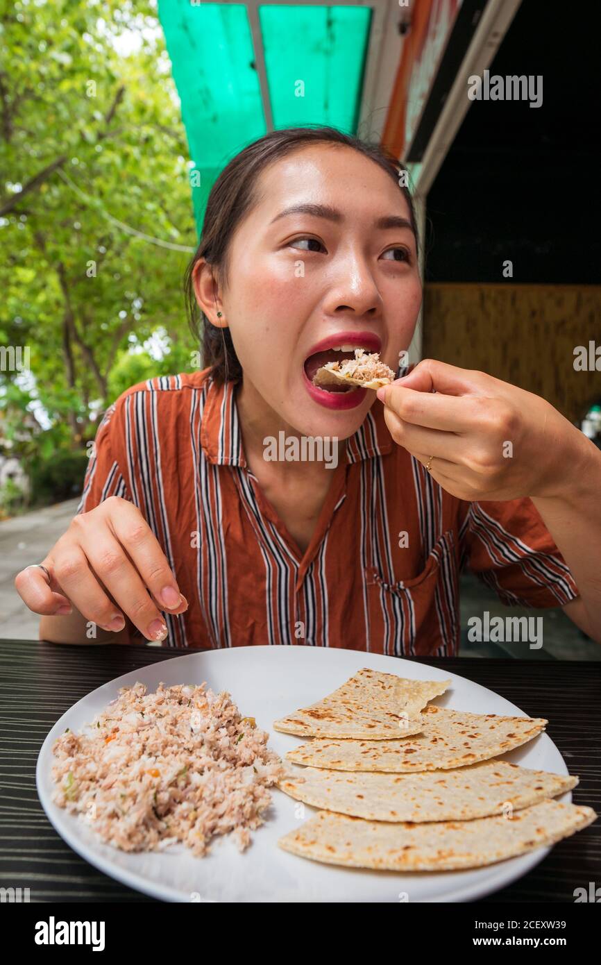 Content ethnic female enjoying delicious Mas Huni with chapati bread while sitting at table in restaurant during breakfast Stock Photo