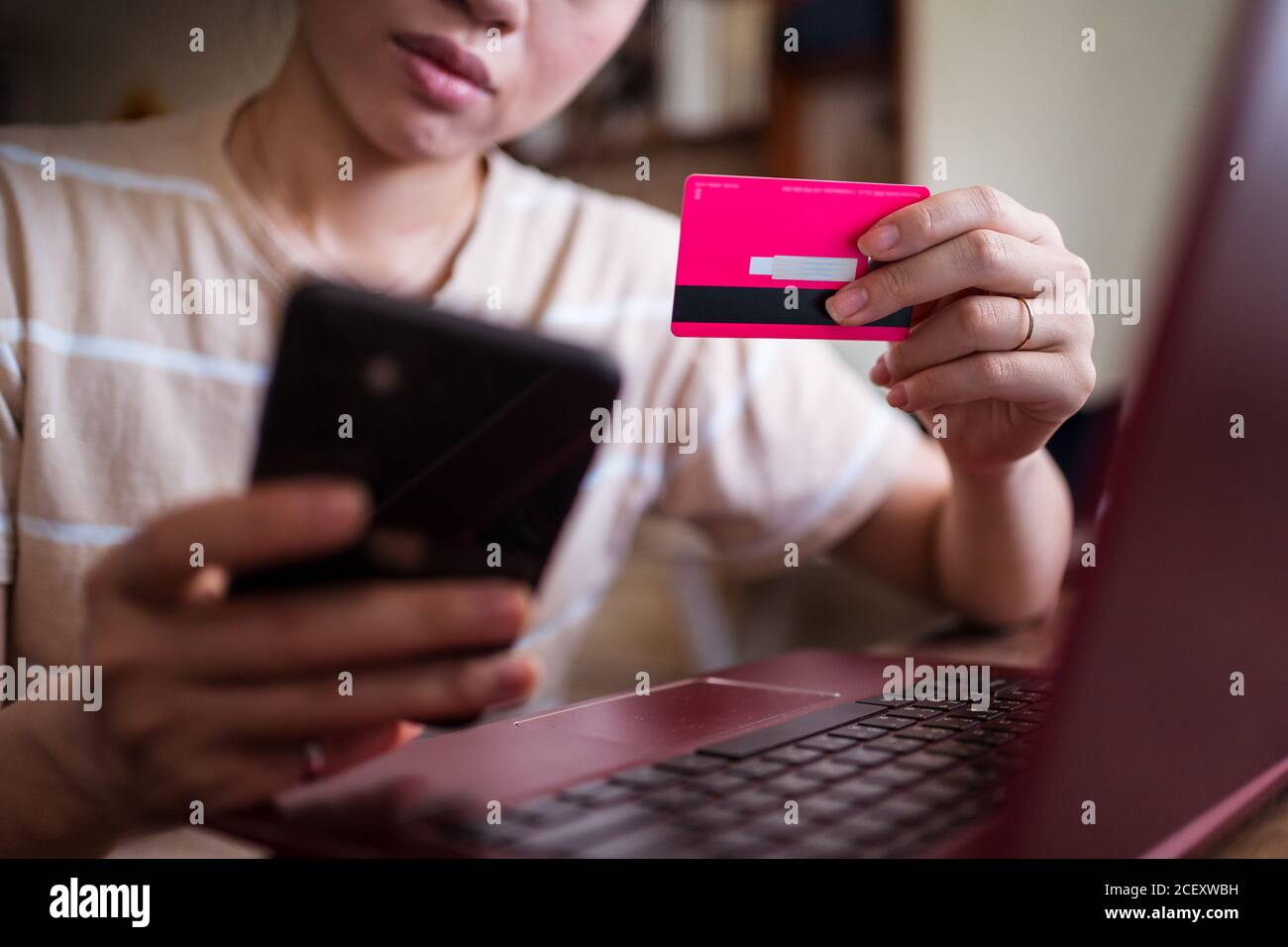 Female sitting at table at home and making payment for online purchases for food via mobile app Stock Photo