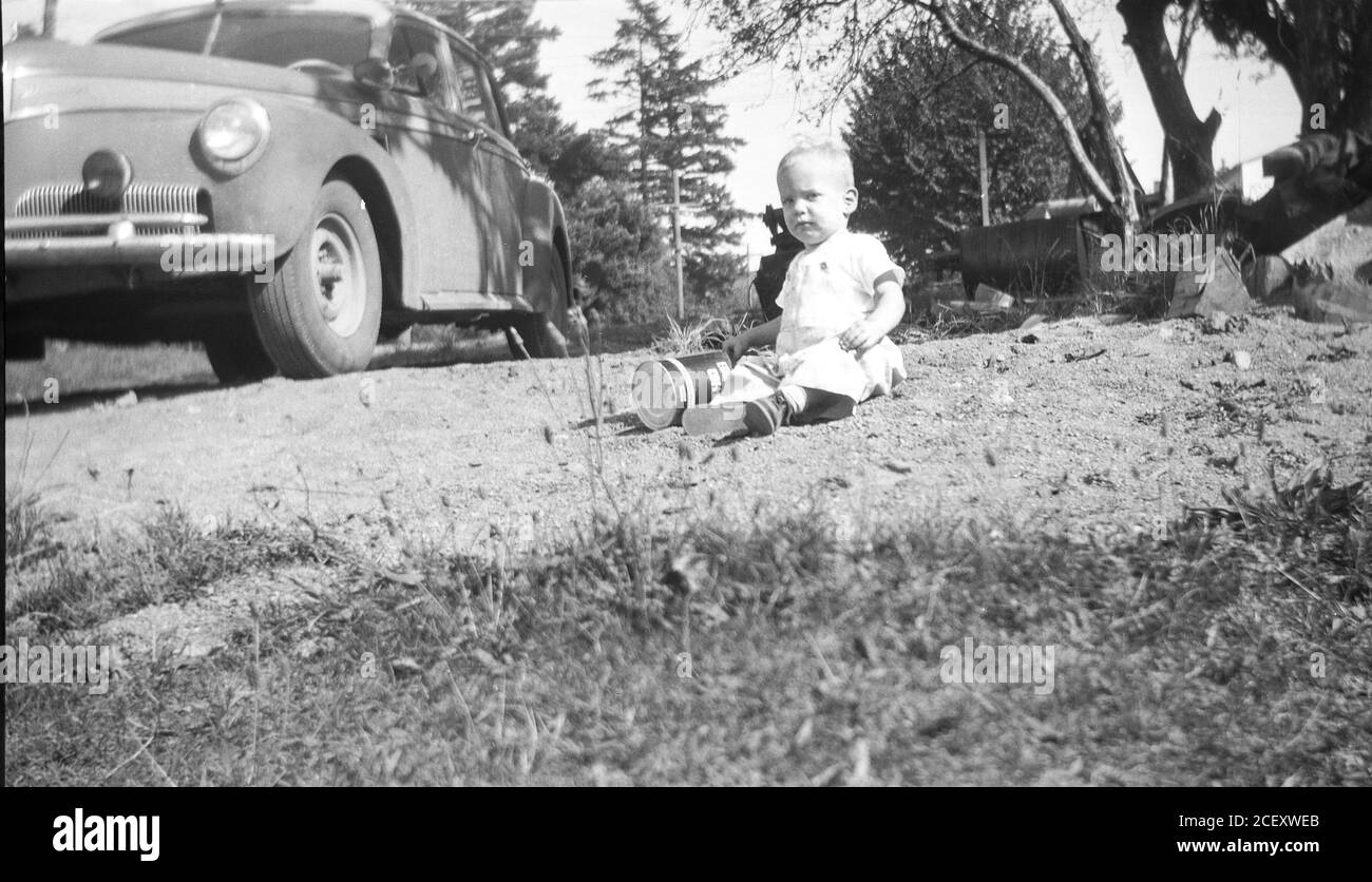 Baby Girl Playing near Parked Car, 1951, USA Stock Photo