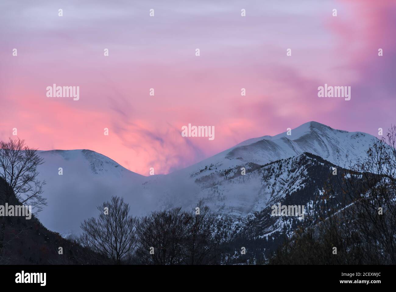 Spectacular landscape of mountain with snowy peak on slope under blue cloudy sky in sunny autumn day Stock Photo