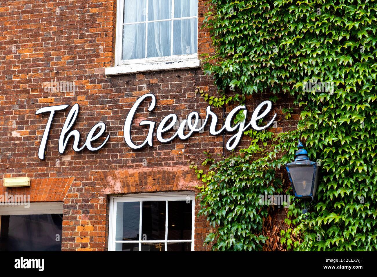 Sign on the red brick facade of The George at Baldock pub and restaurant, Baldock, UK Stock Photo