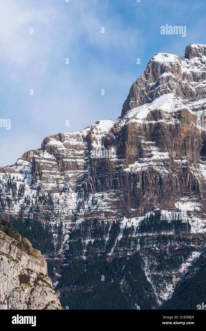 Spectacular landscape of mountain with snowy peak on slope under blue cloudy sky in sunny autumn day Stock Photo