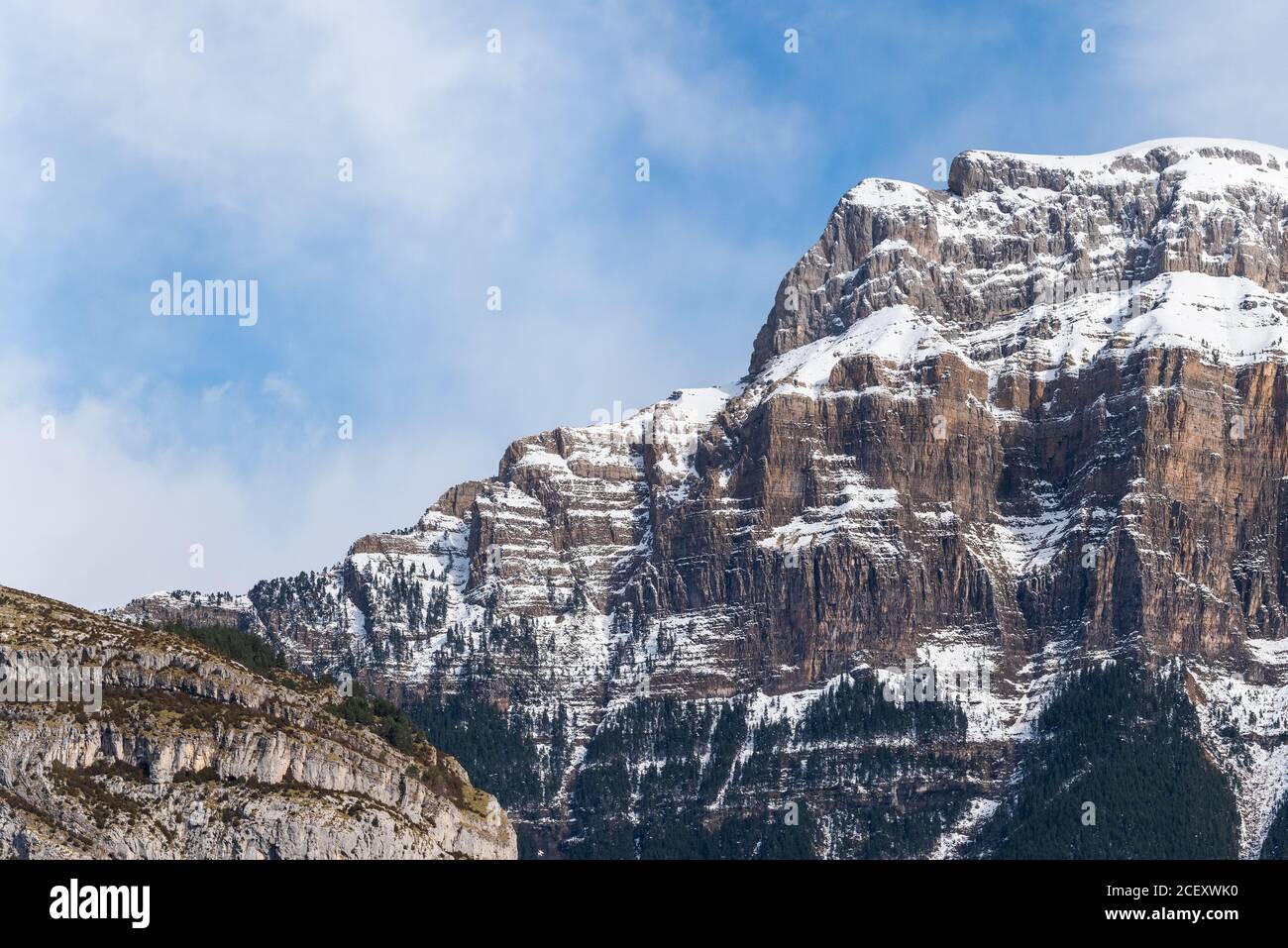 Spectacular landscape of mountain with snowy peak on slope under blue cloudy sky in sunny autumn day Stock Photo