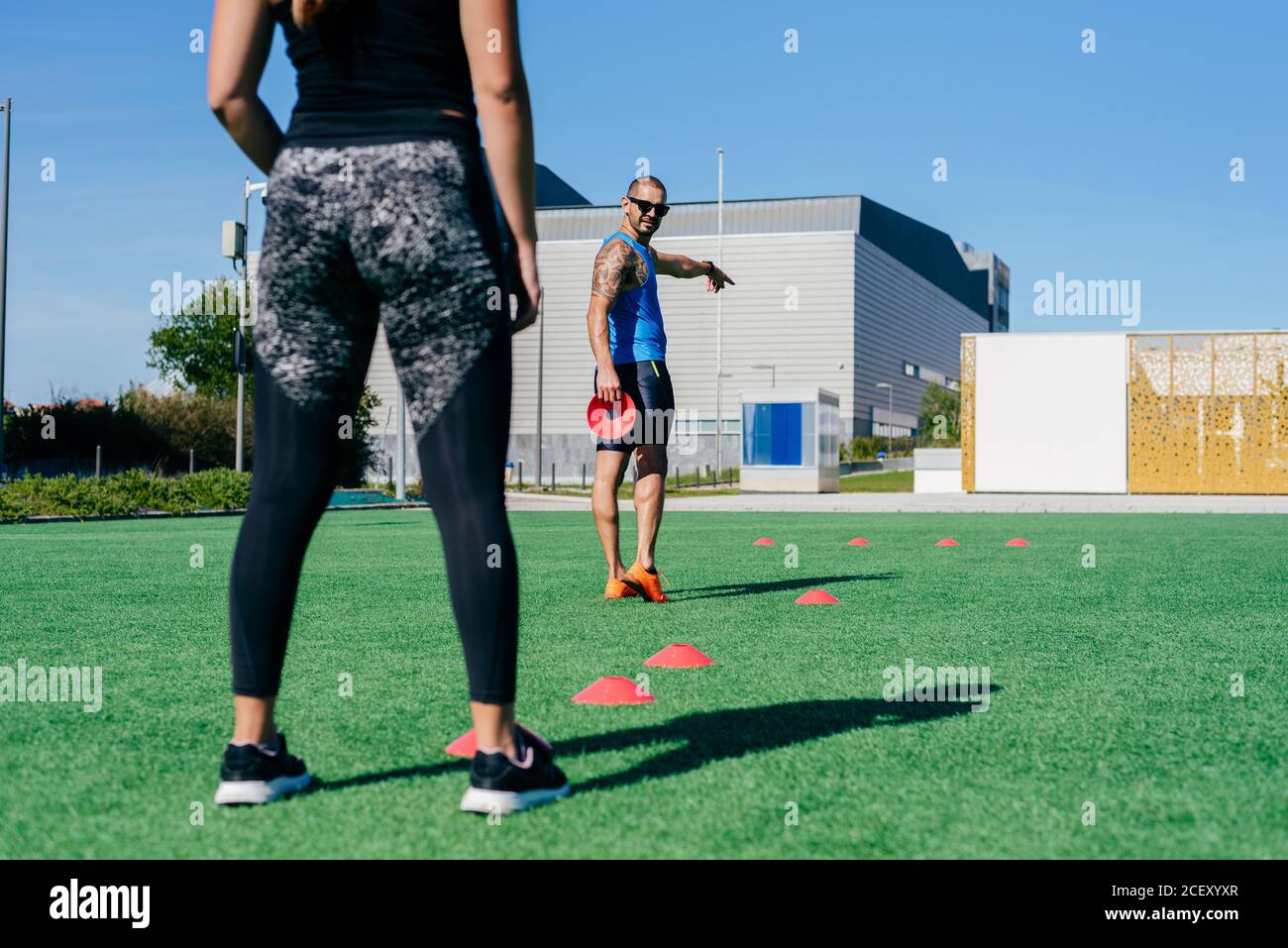 Crop young athletic female performing agility exercise with training cones during fitness