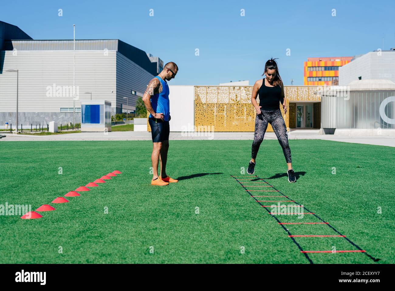 Full body young female athlete jumping on agility ladder during fitness