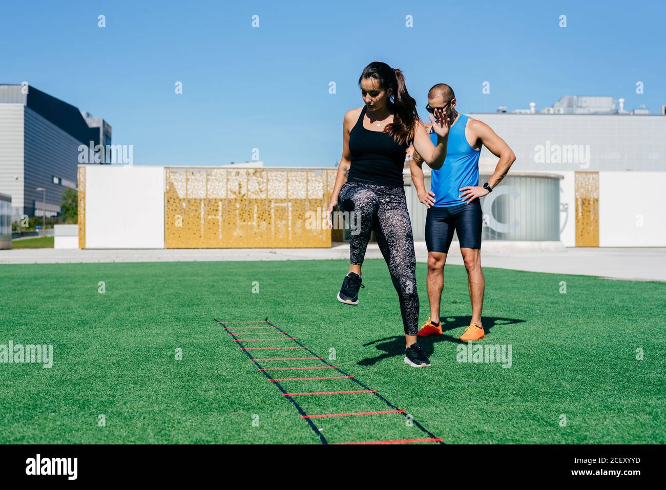 Full body young female athlete jumping on agility ladder during fitness