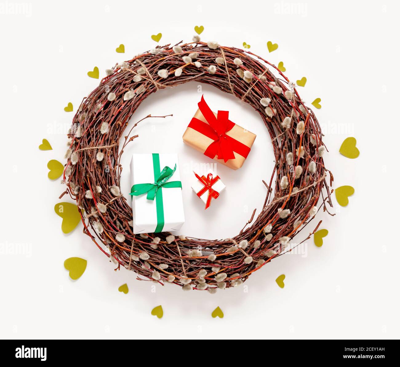 Spring Easter wreath, willow tree branches, present gift boxes and green hearts on white background. Top view, flat lay Stock Photo