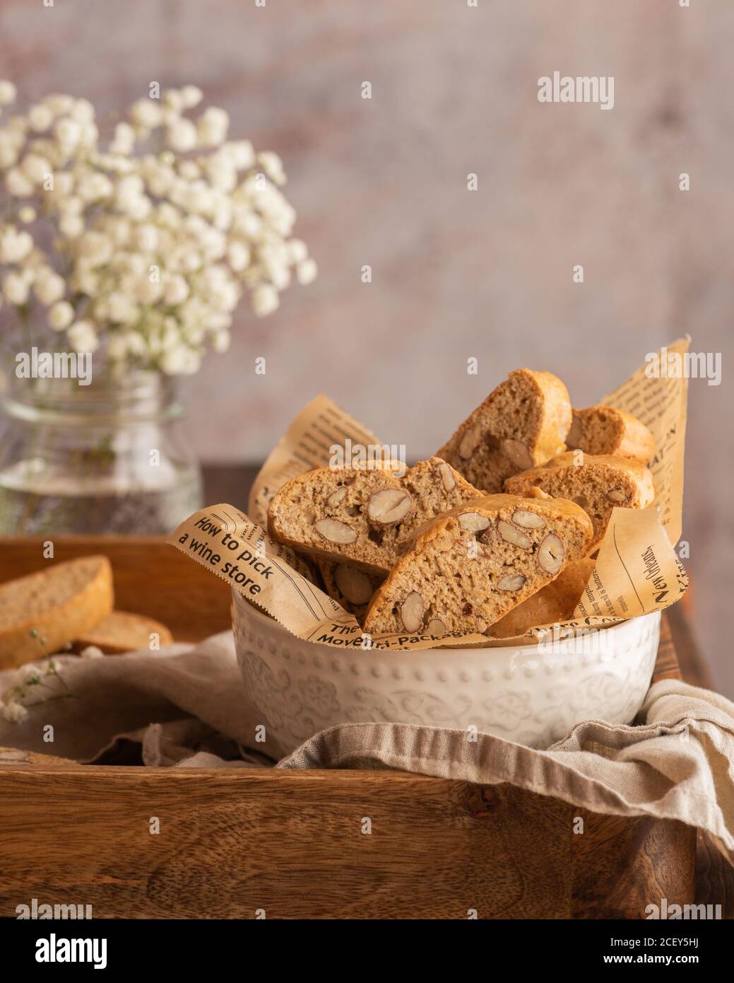Bowl with typical Catalan pastry carquinyolis with almonds served on wooden table with bouquet of flowers Stock Photo