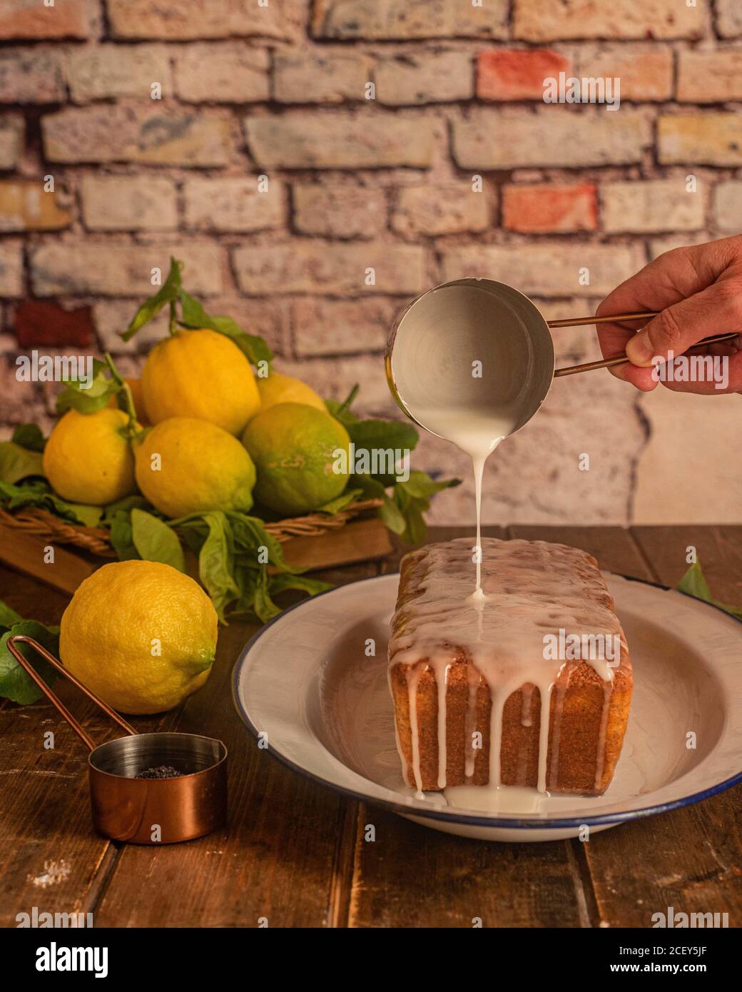 Crop unrecognizable cook spilling white sugar glaze over baked lemon