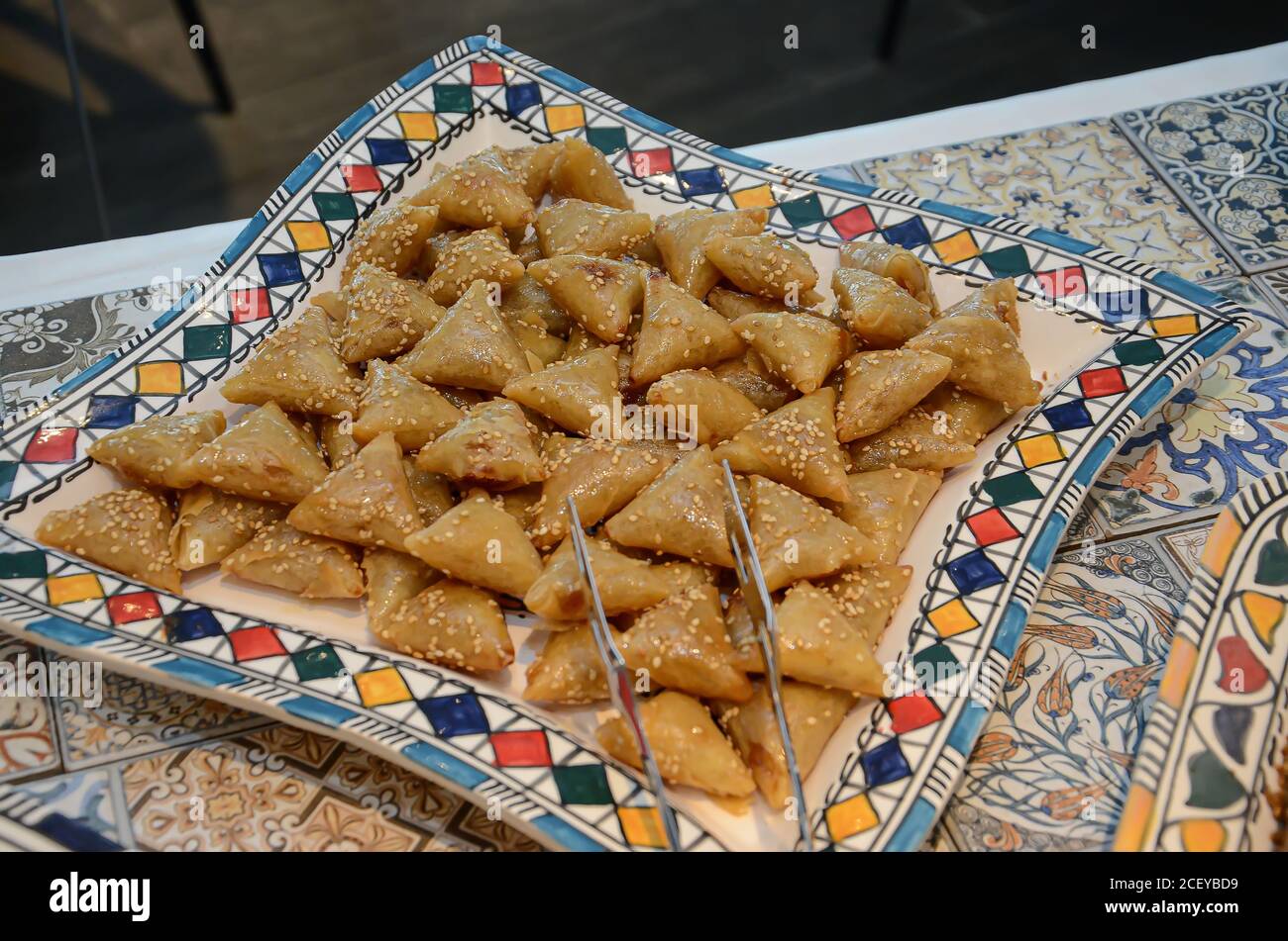 A tasty and sweet plate full of fresh traditional Moroccan handmade Brewat sweets on a fine white fabric surface ready for the celebration of EId Al-A Stock Photo