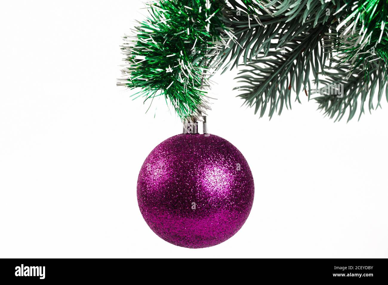 Purple Christmas ball on a spruce branch decorated with tinsel, white background, isolate. close-up Stock Photo