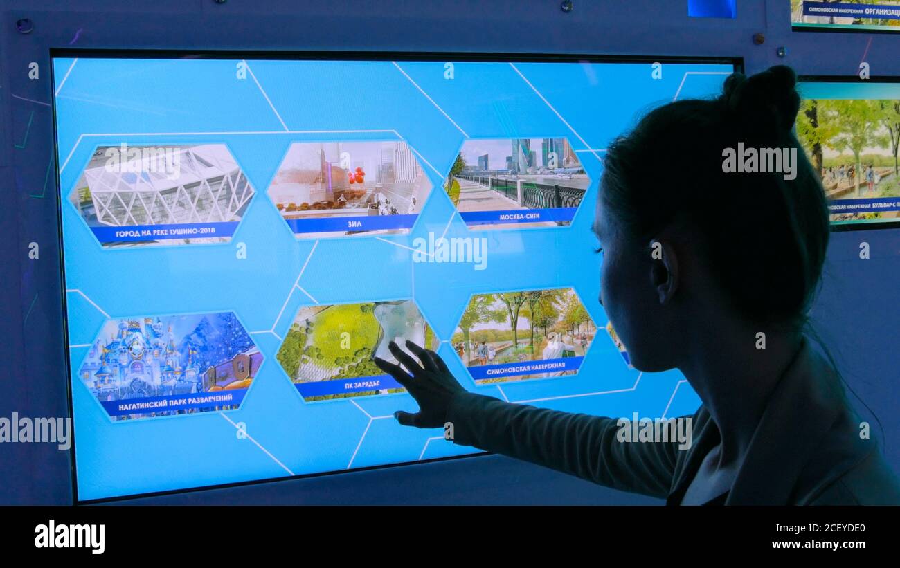 MOSCOW, RUSSIA - July 30, 2018: Smart City Exhibition. Woman using interactive touchscreen display at modern technology show Stock Photo