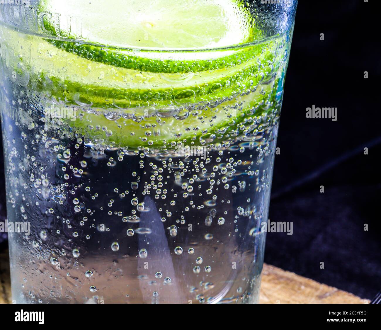 a glass of soda and lime slices in it on a dark background Stock Photo