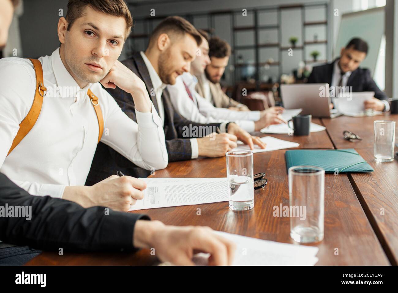 serious confident men in suits sit in office coworking, making notes, using papers. discuss and write business ideas Stock Photo