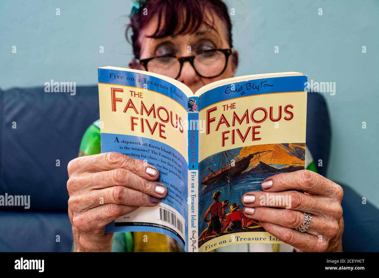 Elderly woman reading The Famous Five by Enid Blyton Stock Photo