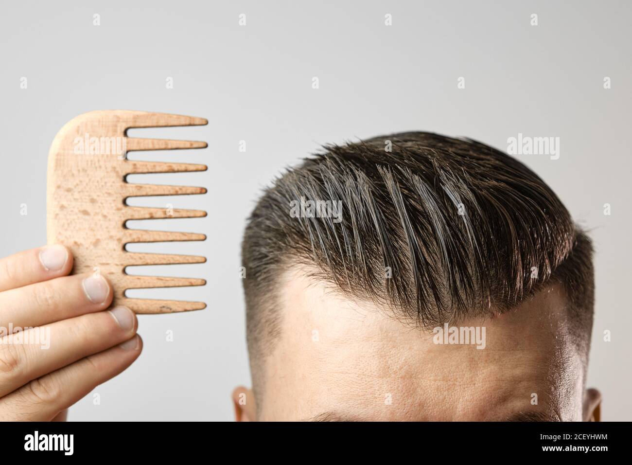 Man brushing his hair with a wooden comb and show how to take care
