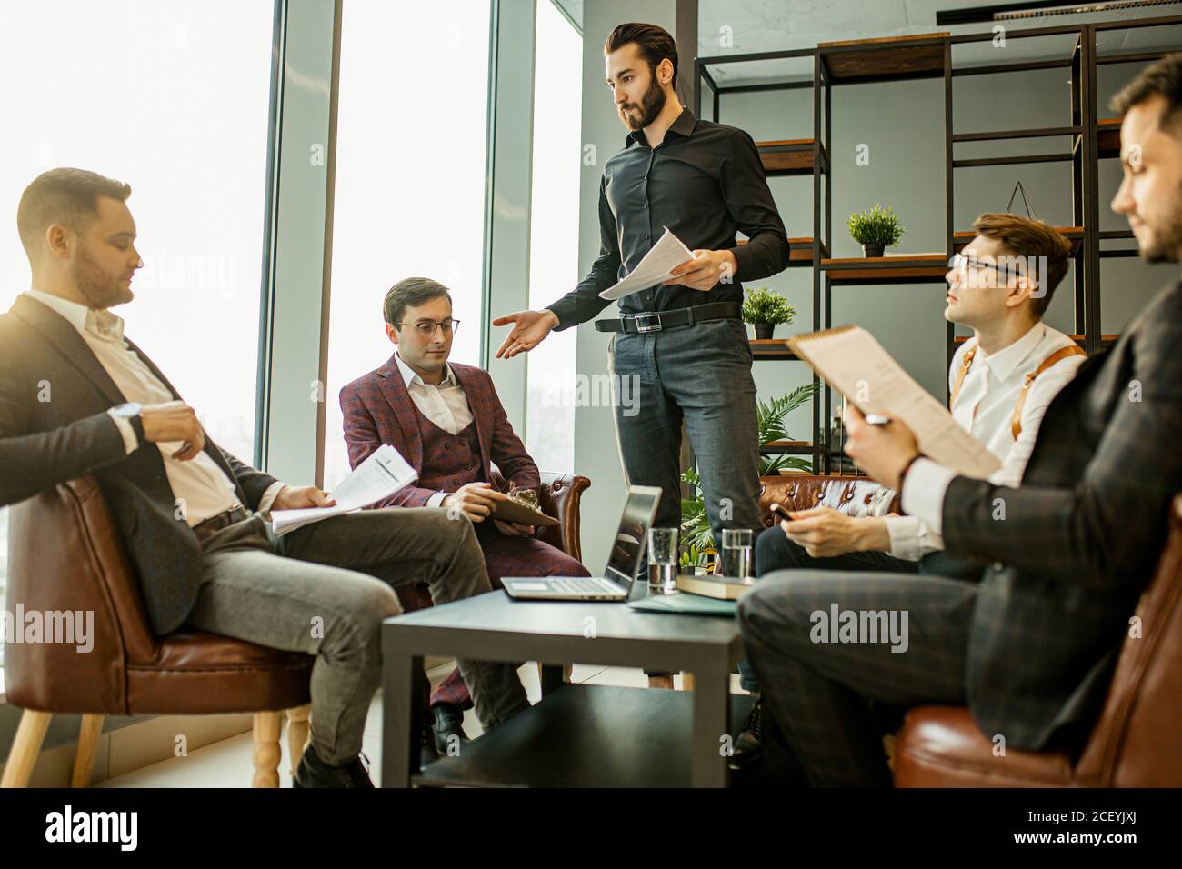 young confident men developing new business startup, discussing interaction in finance and market, sharing opinions and ideas with each other, dressed Stock Photo