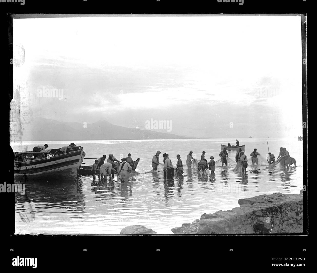 Turkish fishermen preparing their equiment and fishernet for the next fishing. Turkey, presumably near Izmir (Smyrna). Photograph on dry glass plate from the Herry W. Schaefer collection, around 1913. Stock Photo