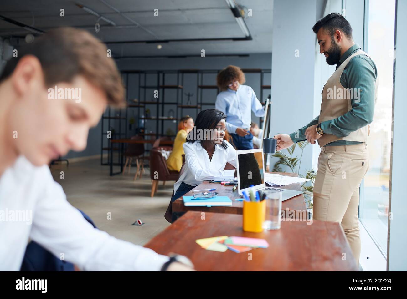 While working in office. Young business leaders sitting on table in the process of co-working, writing Stock Photo