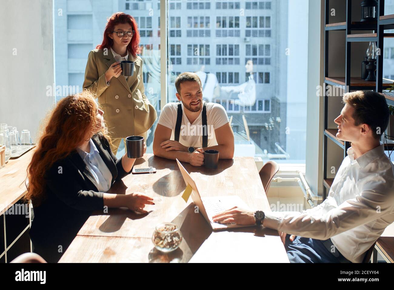 Lively discussion between young businessmen, female investor and personal assistant and having coffee during a business appointment. Professionals sha Stock Photo