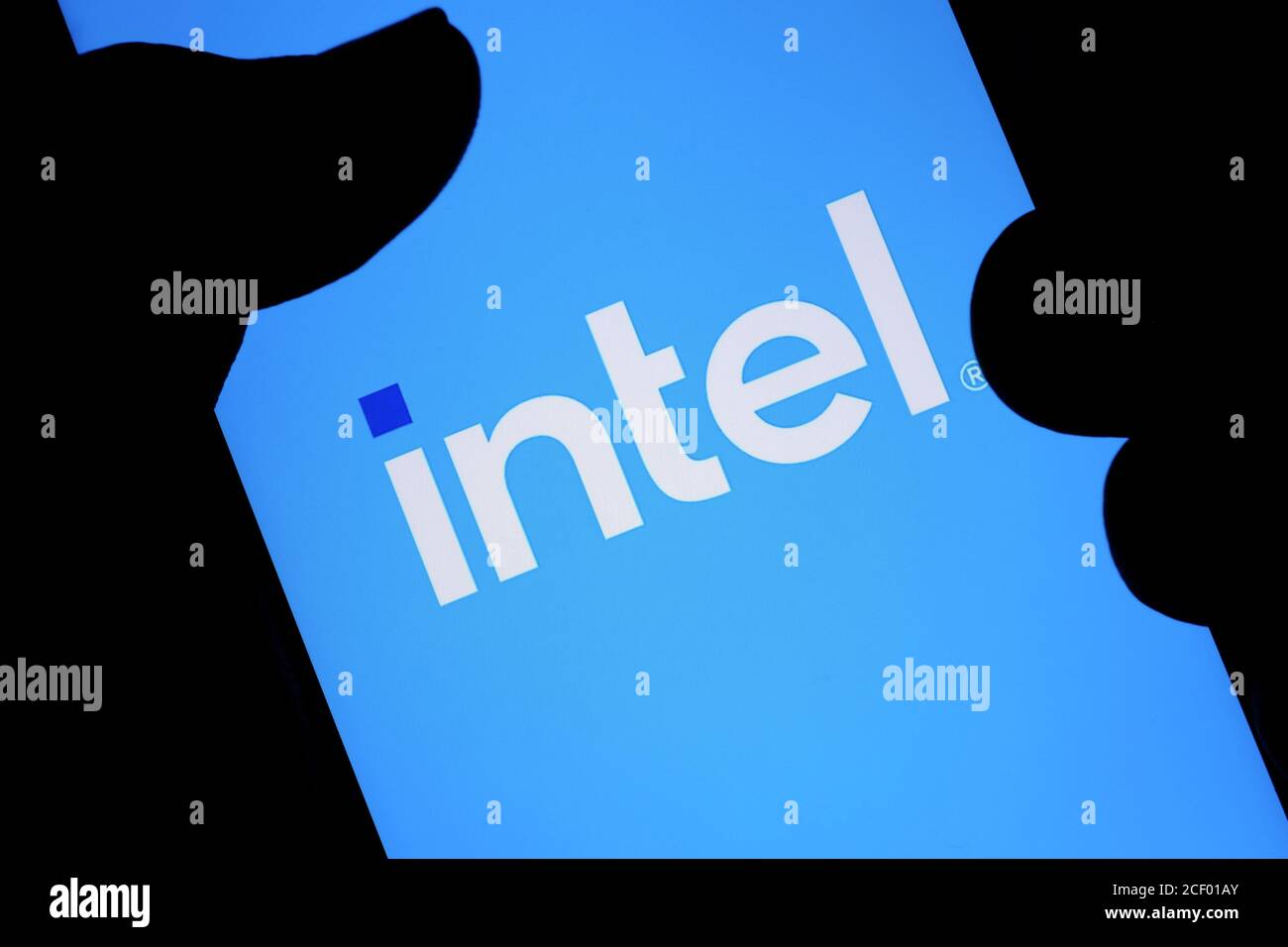 New Intel logo seen on the screen and blurred fingertip touching it in a dark. Intel presented its rebranded logotype Stock Photo