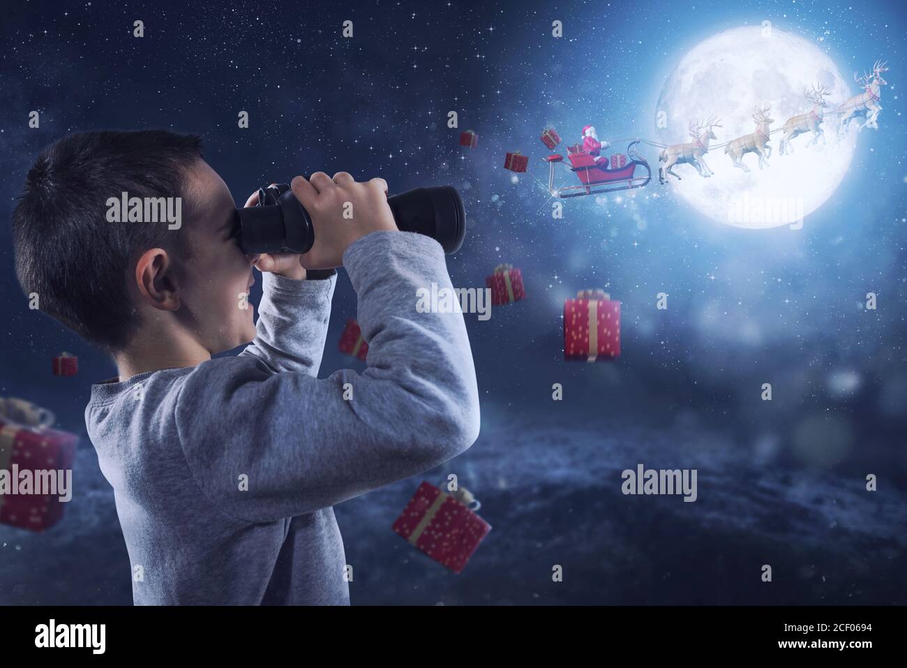 Happy child with binocular watches santa claus who fly with reindeers Stock Photo