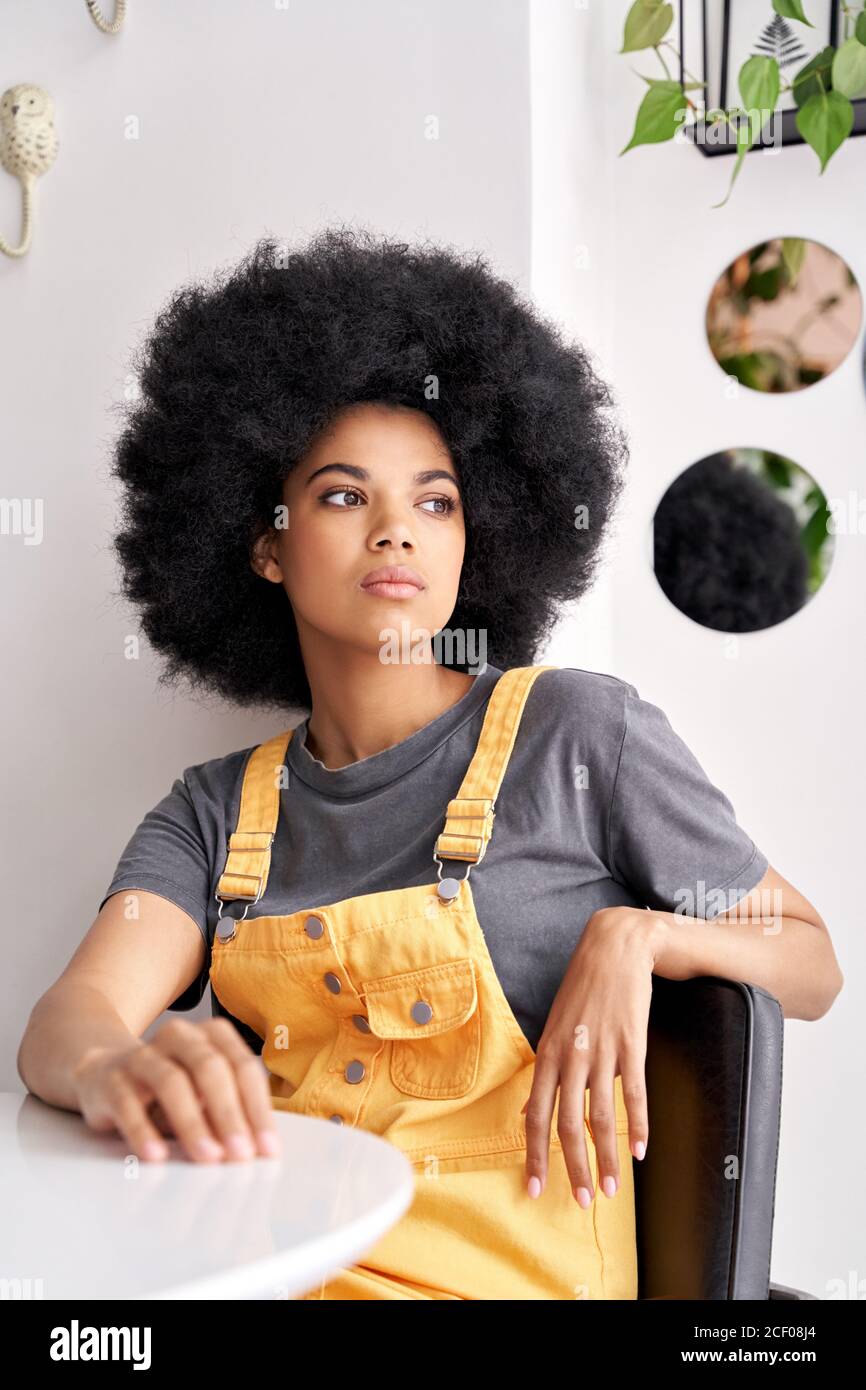 Thoughtful pensive African lady looking through window sitting at cafe table. Stock Photo