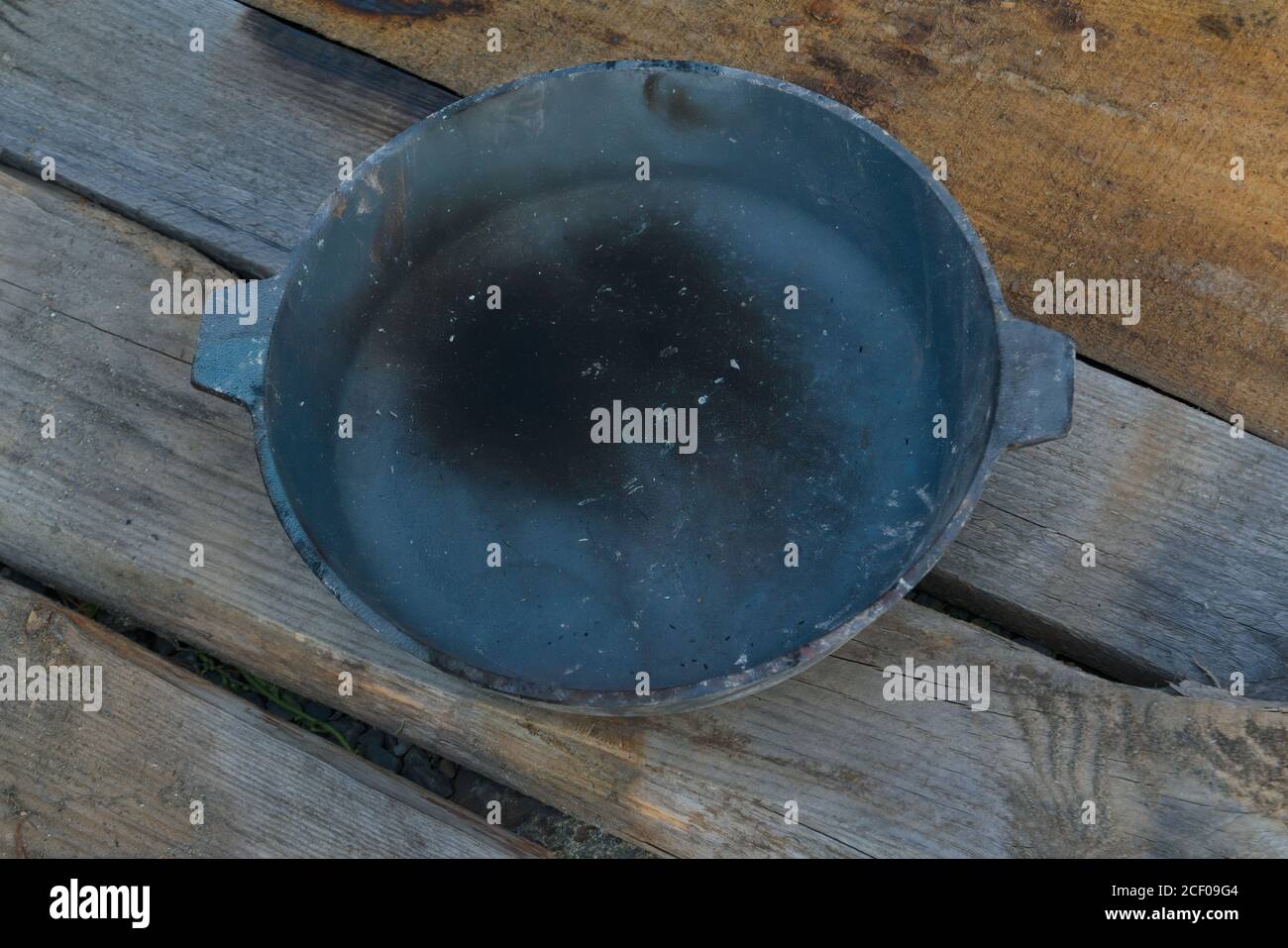 Old smoked cast-iron frying pan on a wooden table background close-up ...