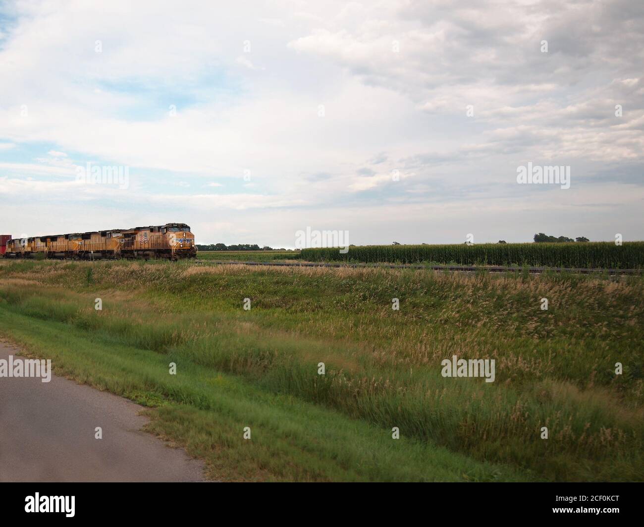 WOOD RIVER, NEBRASKA - JULY 26, 2018: A bright yellow Union Pacific Railroad train approaches a corn field as it crosses the rural Nebraska farmlands Stock Photo