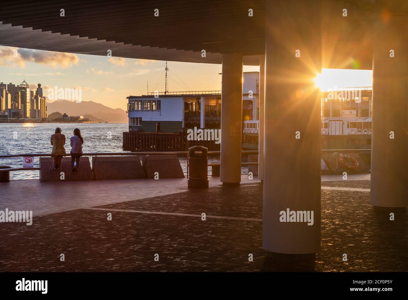 Women sitting next to Star Ferry Pier, Tsim Sha Tsui, Kowloon, Hong Kong Stock Photo