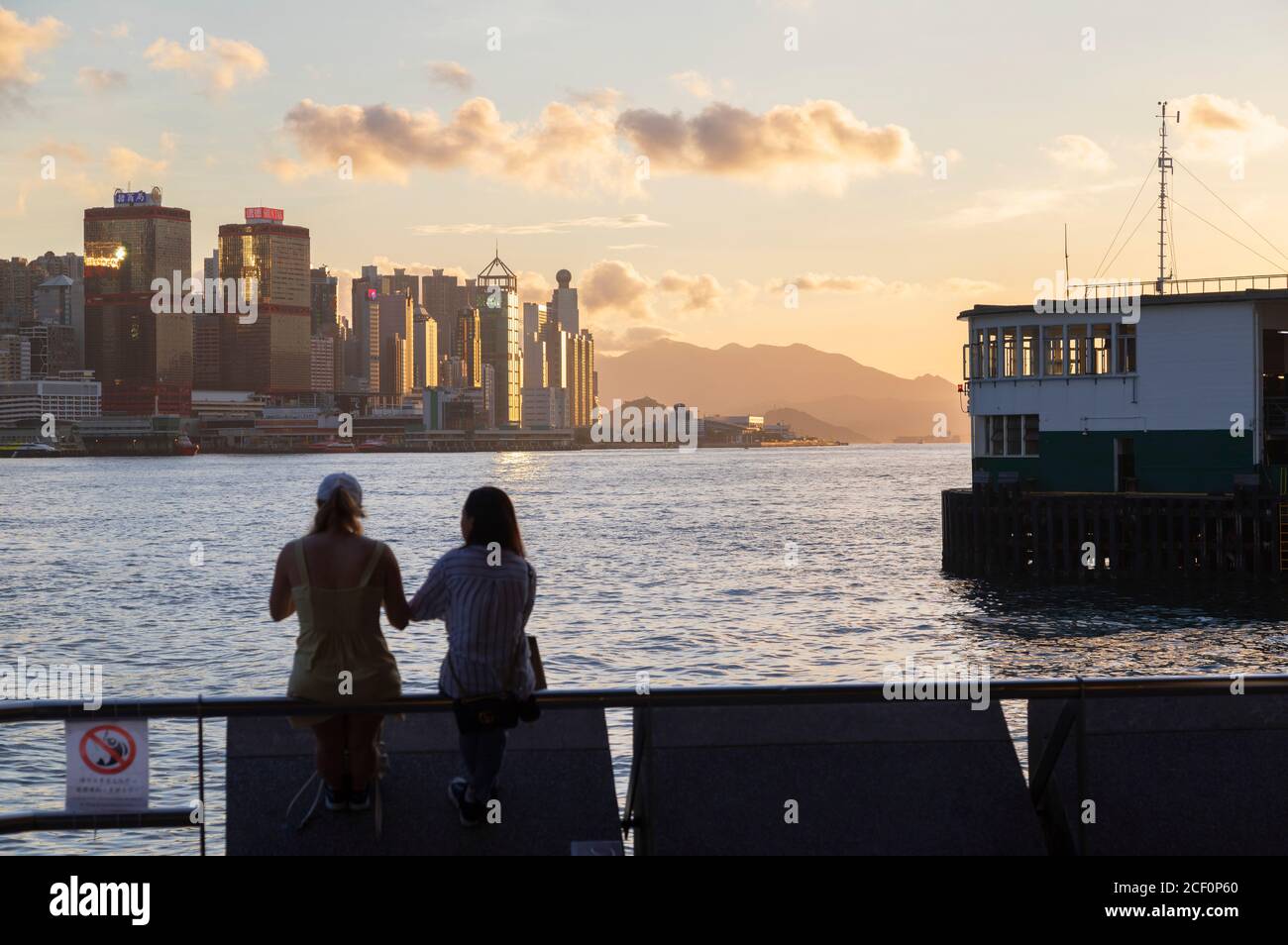 Women sitting next to Star Ferry Pier, Tsim Sha Tsui, Kowloon, Hong Kong Stock Photo