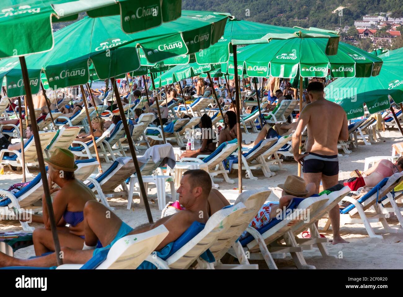 Tourists using umbrellas and sun loungers on the beach at Patong, Phuket, Thailand Stock Photo