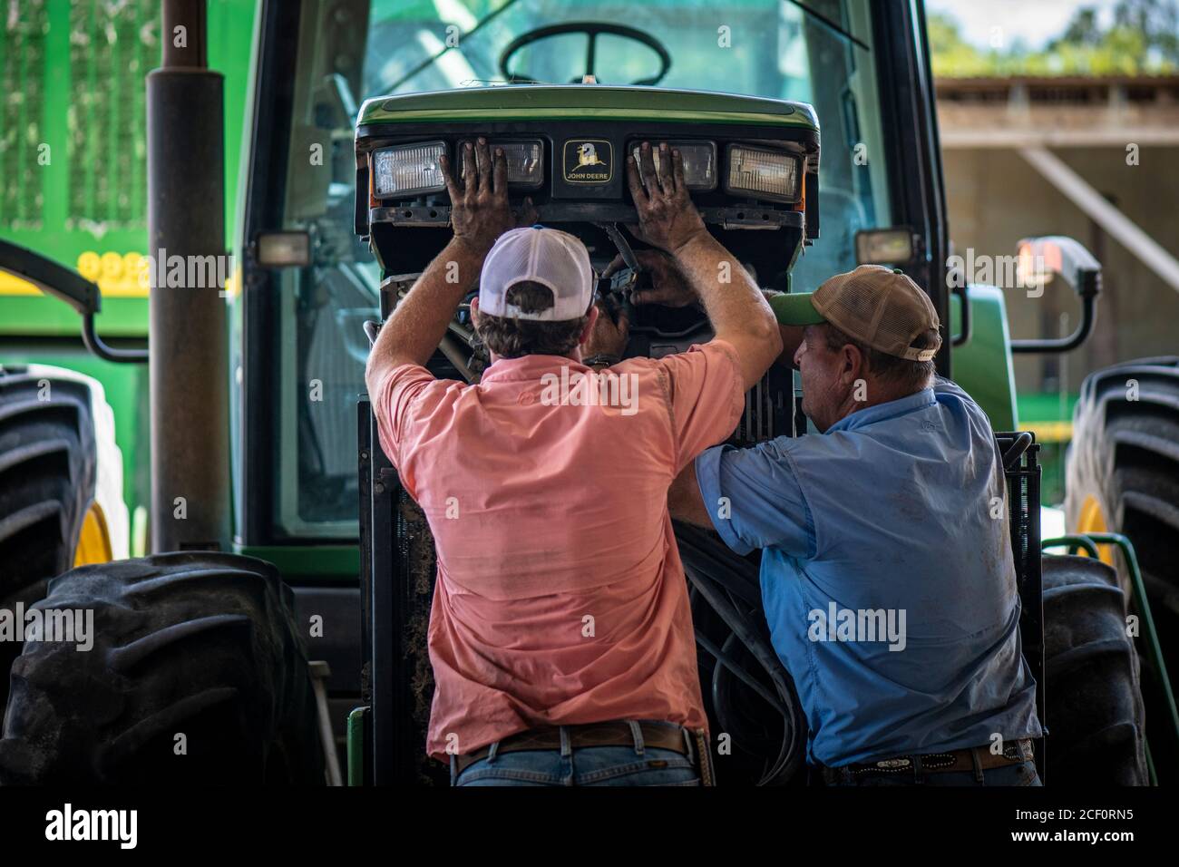 Schirmer Farms (Batesville) Operations Manager Brandon Schirmer, assisted by farm owner and father Ernie Schirmer, puts their John Deere tractor back together, near San Antonio, TX, on August 11, 2020.  They are performing needed farm equipment repairs and maintenance in preparation for the upcoming cotton harvest. Stock Photo