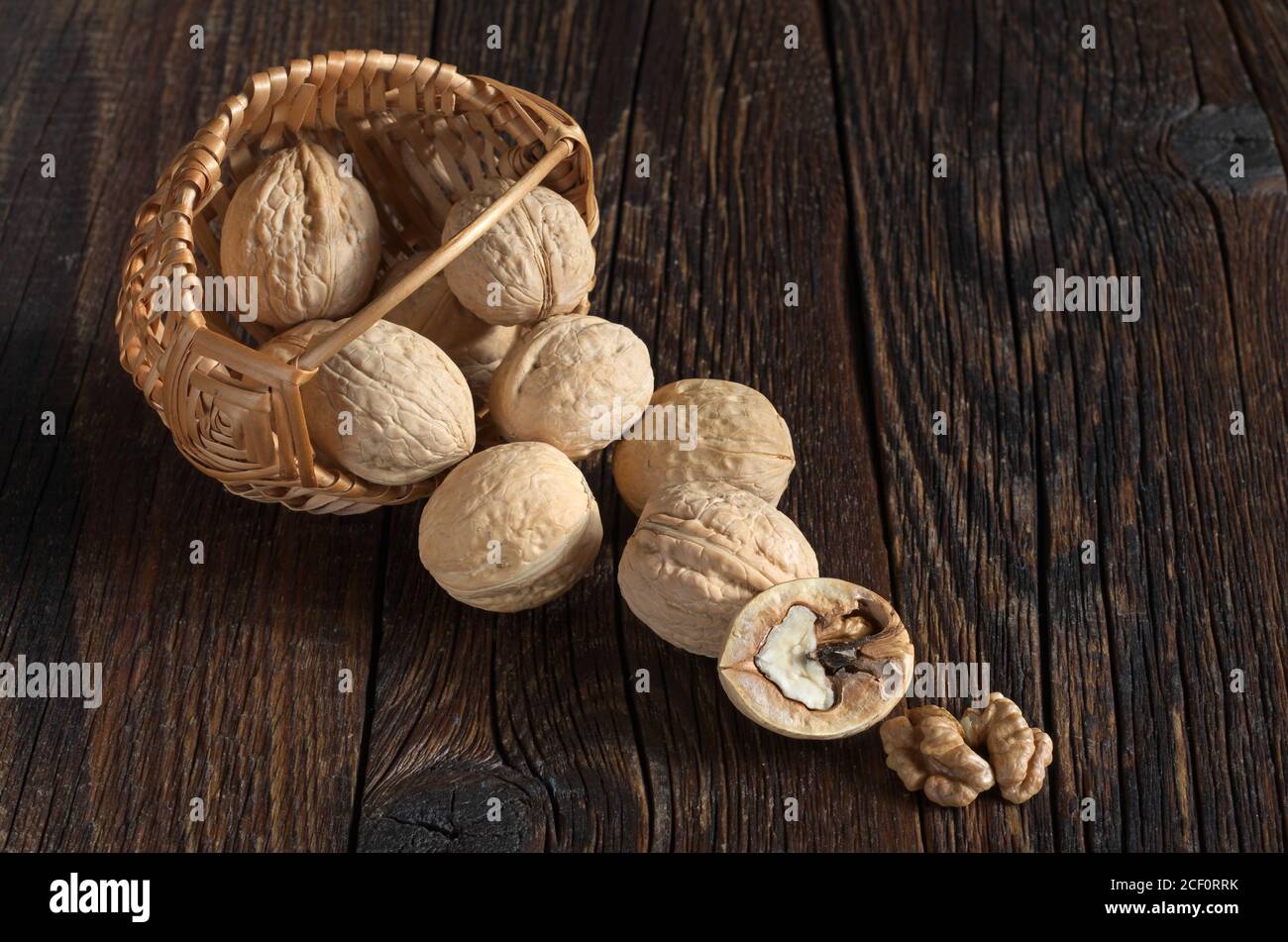Walnut in basket and walnuts kernels on old wooden table Stock Photo