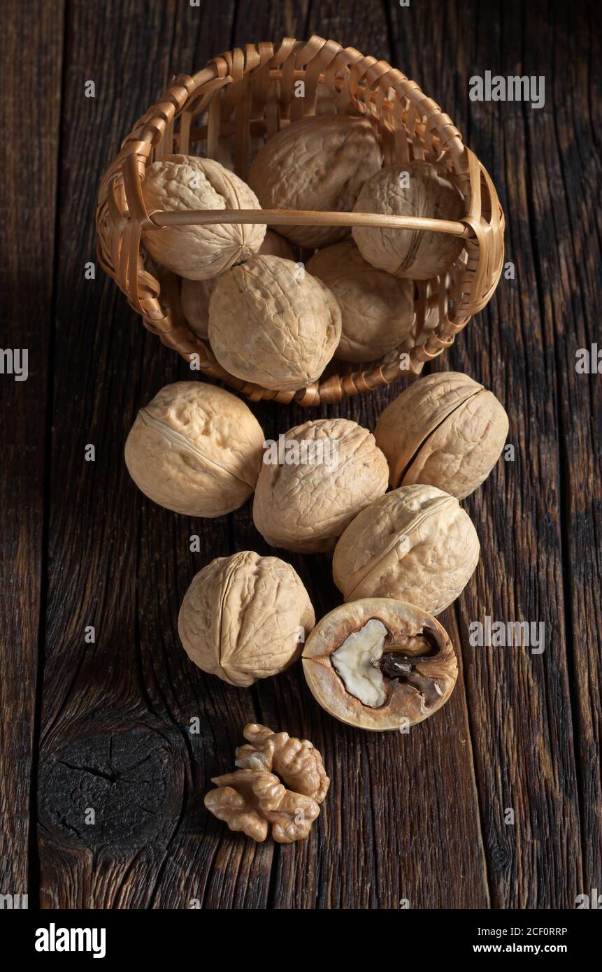 Walnut in basket and walnuts kernels on old wooden table Stock Photo