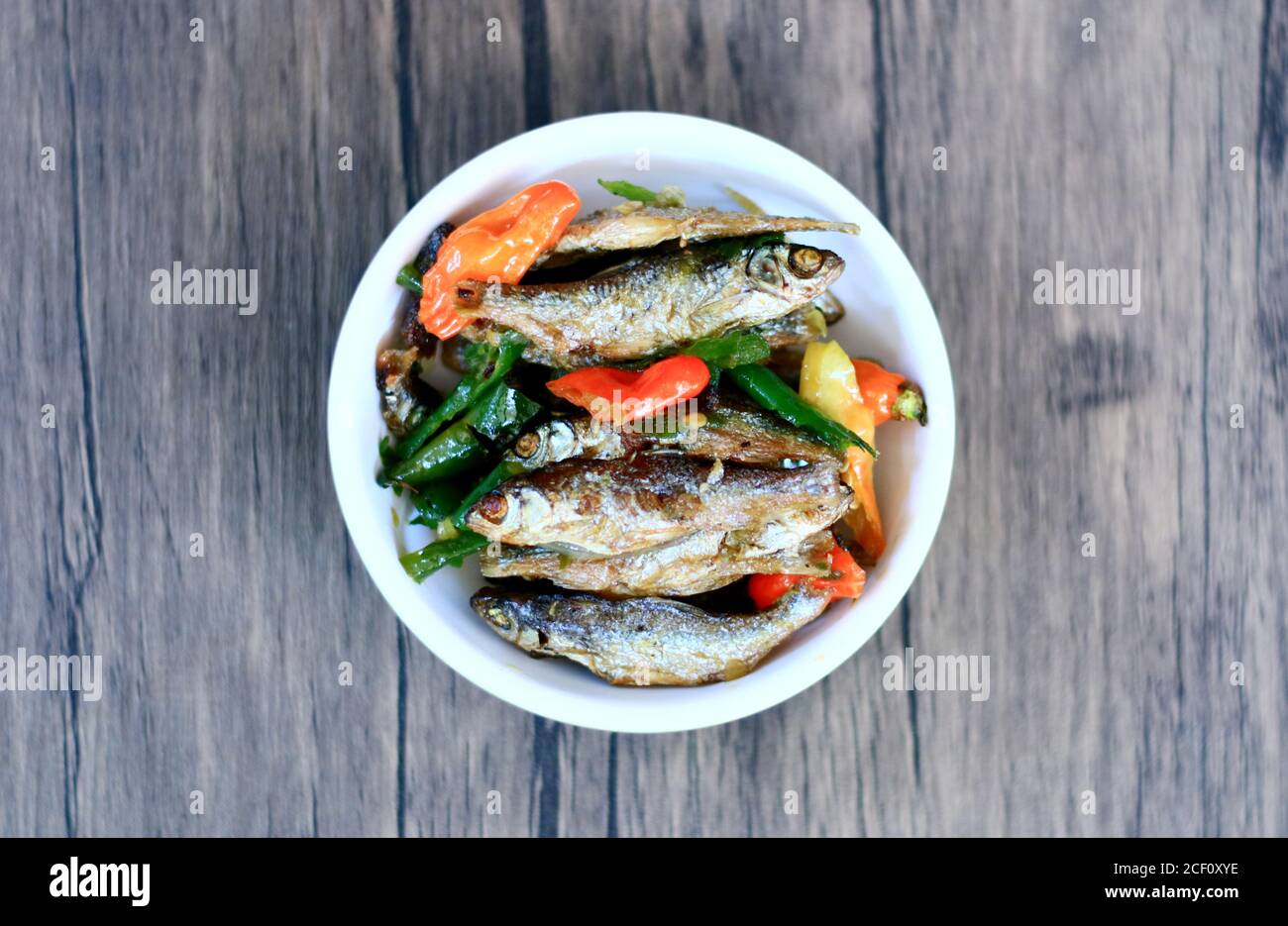 Sauteed anchovy fish or tumis ikan bilis on wood background. Stock Photo