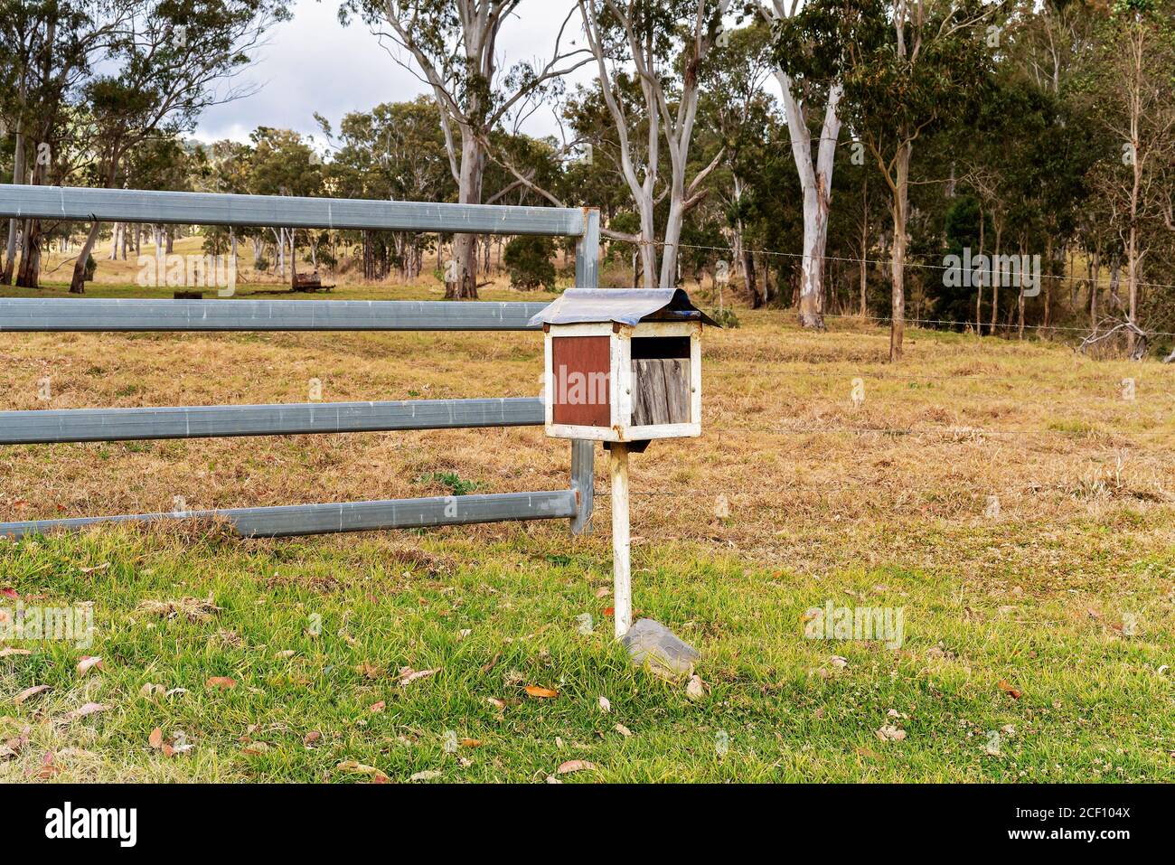 A retro style mail box in front of a fence on a rural property Stock Photo