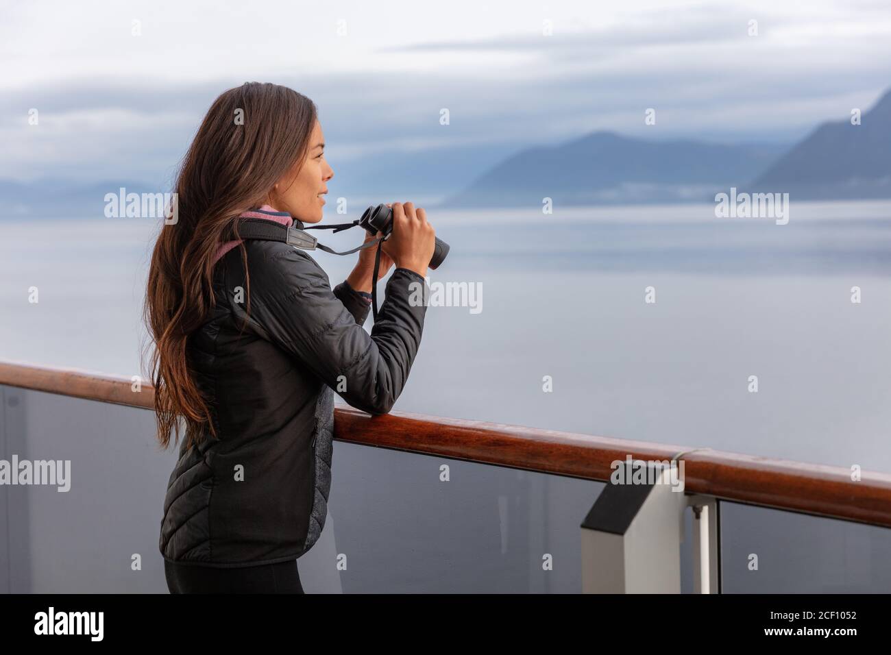 Alaska cruise woman on whale watching boat excursion tour looking at wildlife with binoculars. Tourist at inside passage Glacier Bay destination on Stock Photo