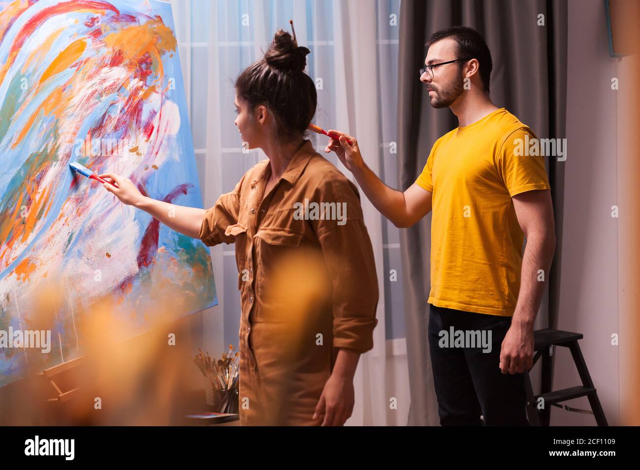 Man and woman painting together on large canvas in art studio. Modern ...