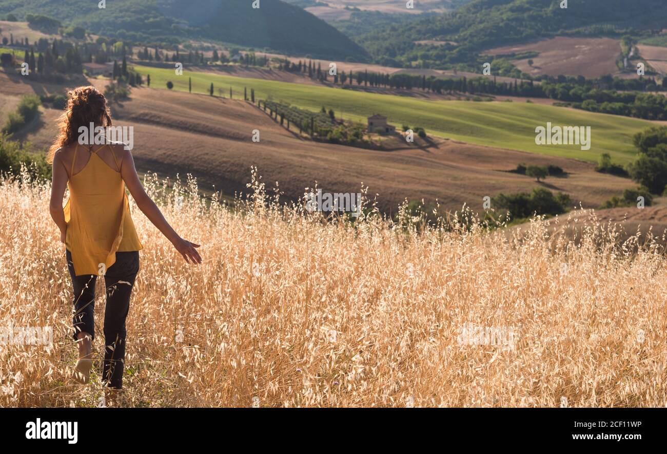 Back view of woman walking in wheat field Stock Photo - Alamy