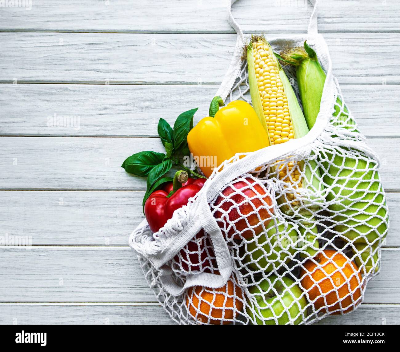Fresh vegetables and fruits on eco string bag on a white wooden ...