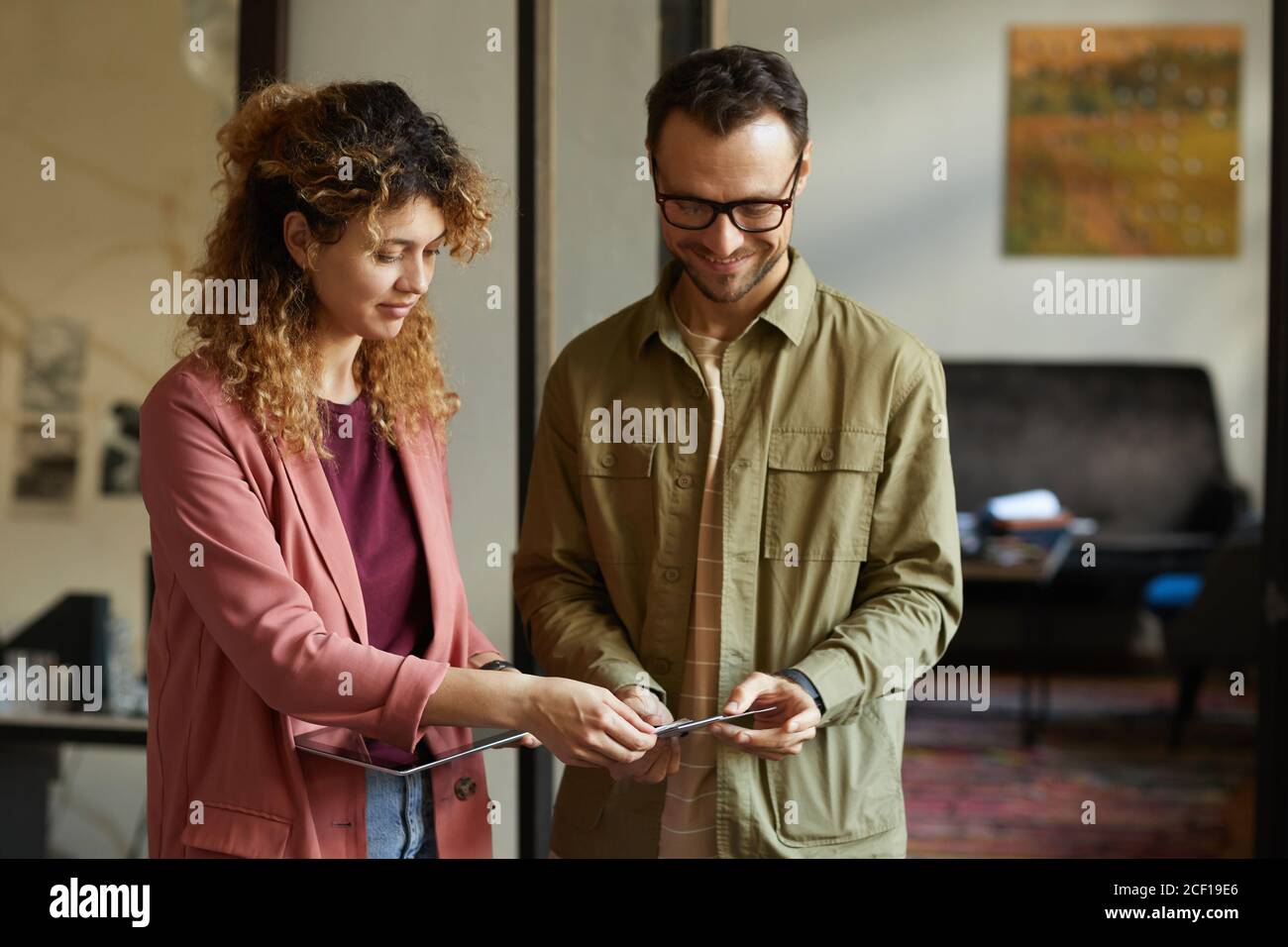 Two designers using digital tablet and discussing patterns for their new project while standing at office Stock Photo