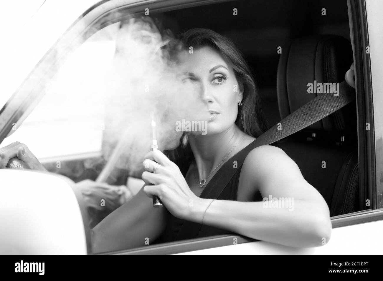Pretty woman smoking the e-cigarette while driving a car Stock Photo