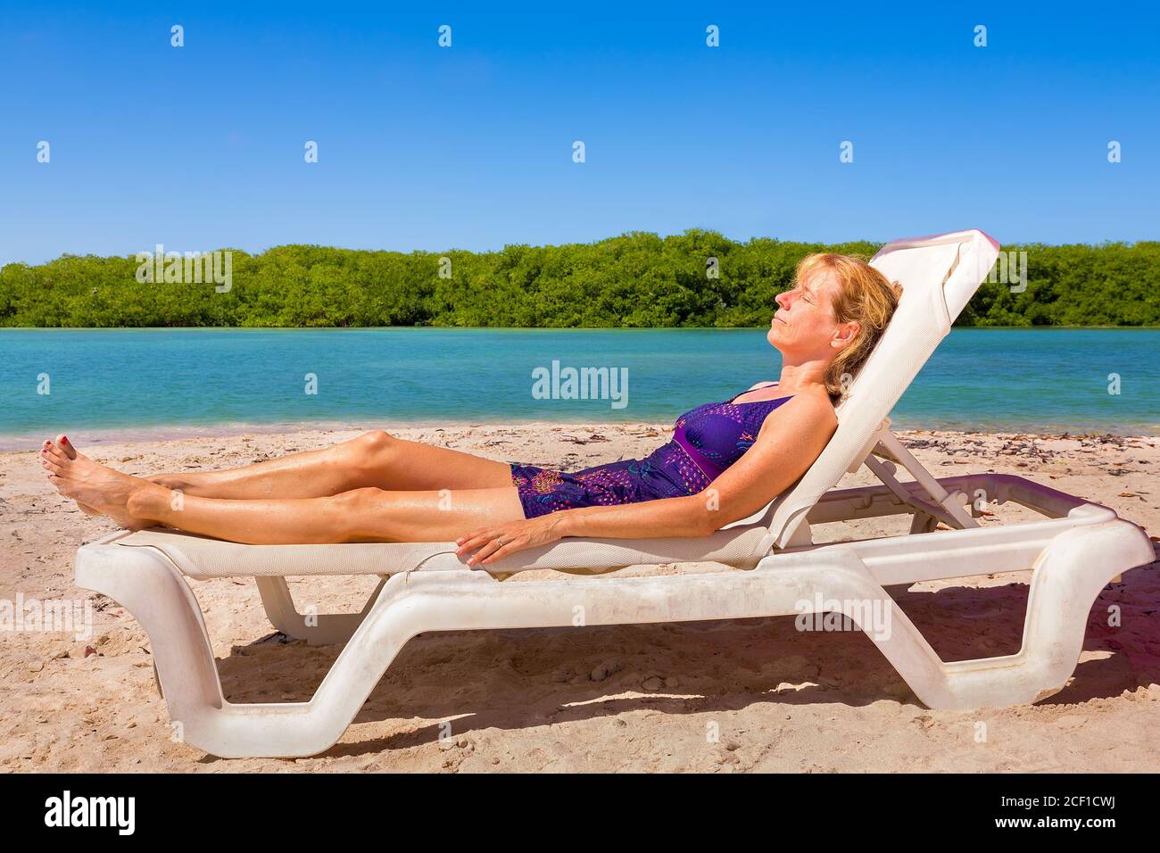 Caucasian woman sunbathes on beach bed by the sea on island Bonaire Stock Photo