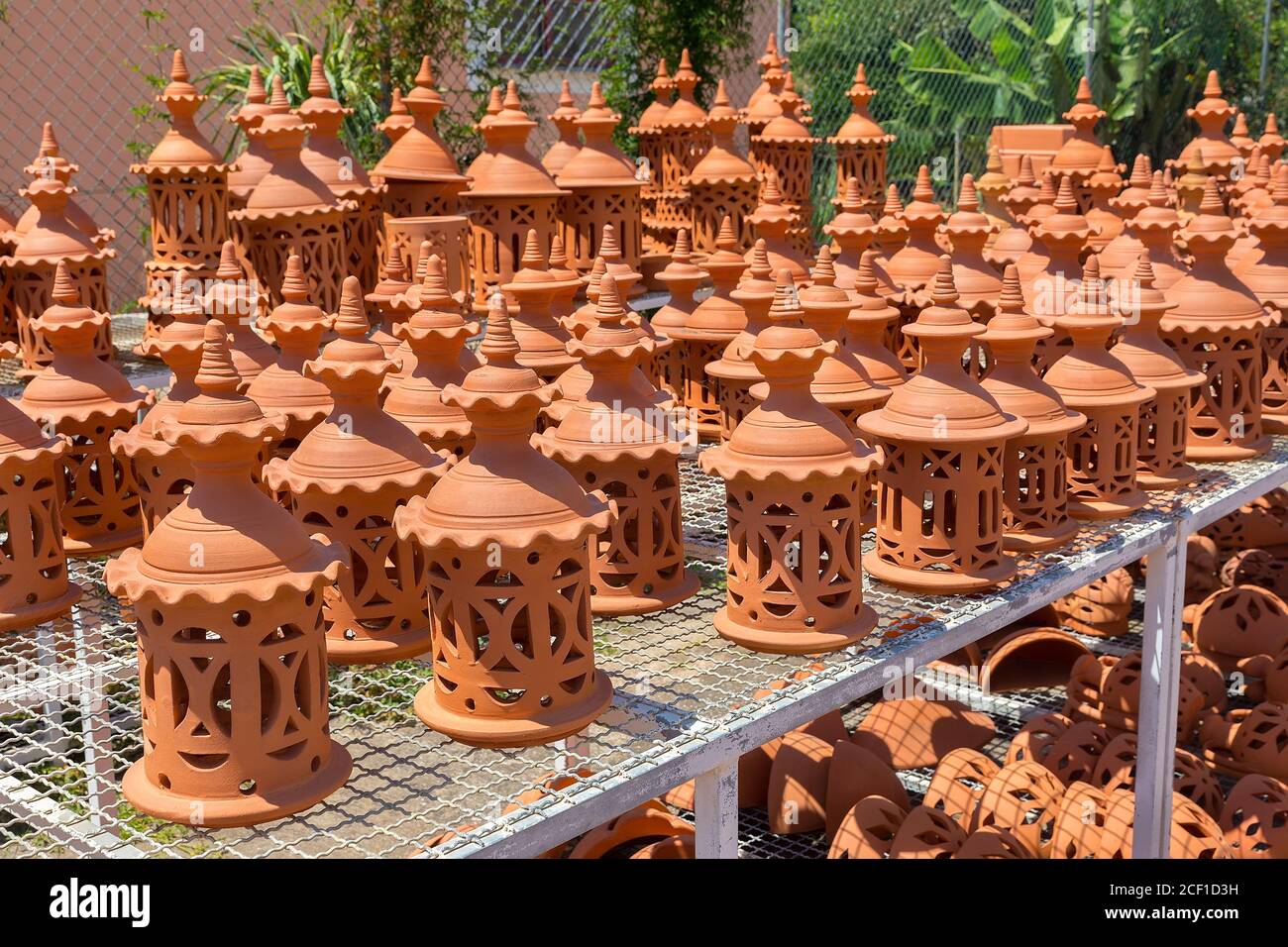 Many orange clay pots on rack outdoors at pottery shop Stock Photo