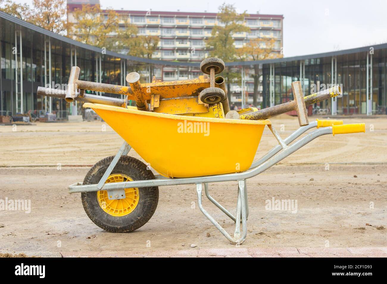Yellow wheelbarrow with stone cutter on new square pavement Stock Photo